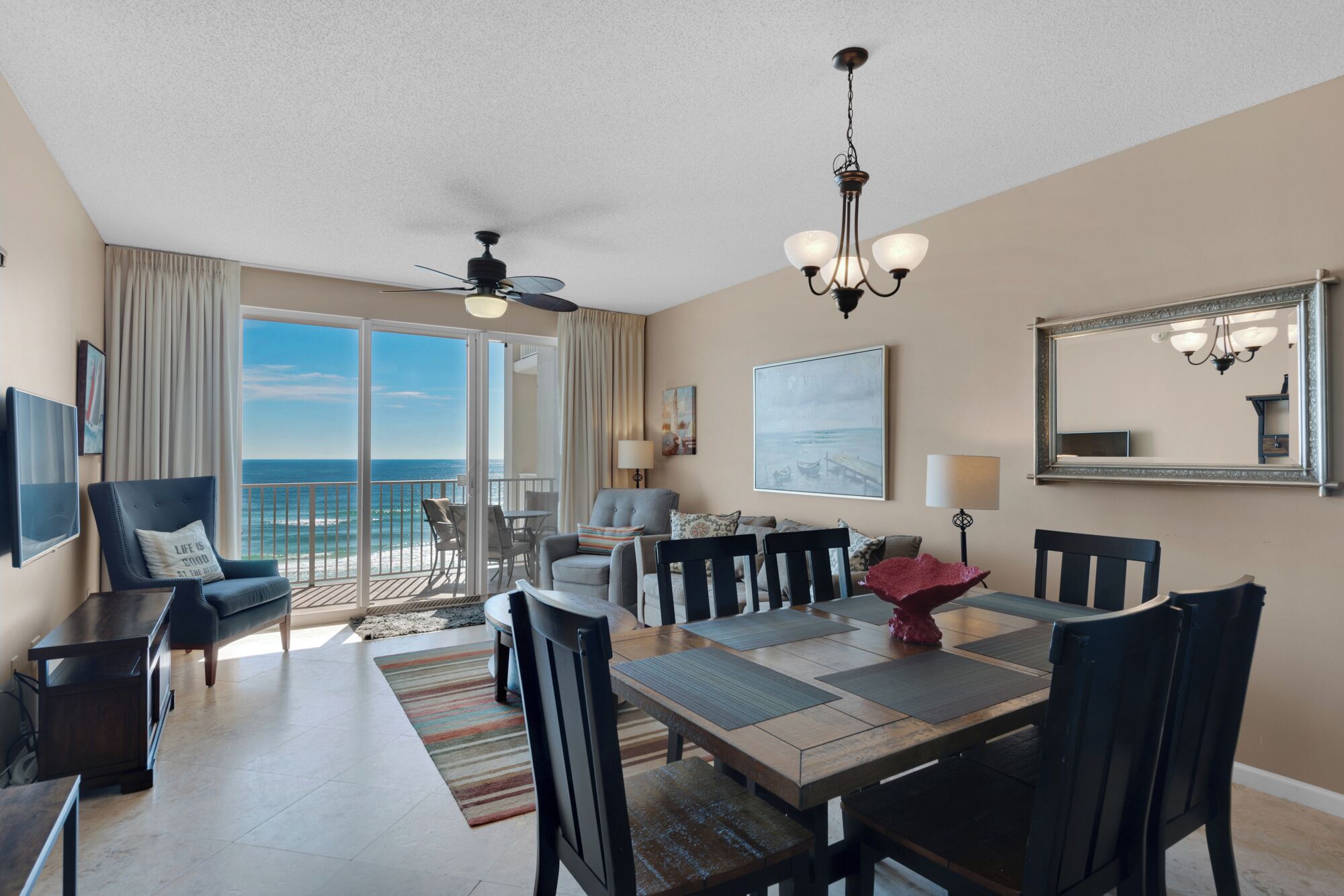A spacious living room with a balcony, a dining area, and a ceiling fan.