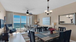 Un salon spacieux avec balcon, un coin repas et un ventilateur de plafond.