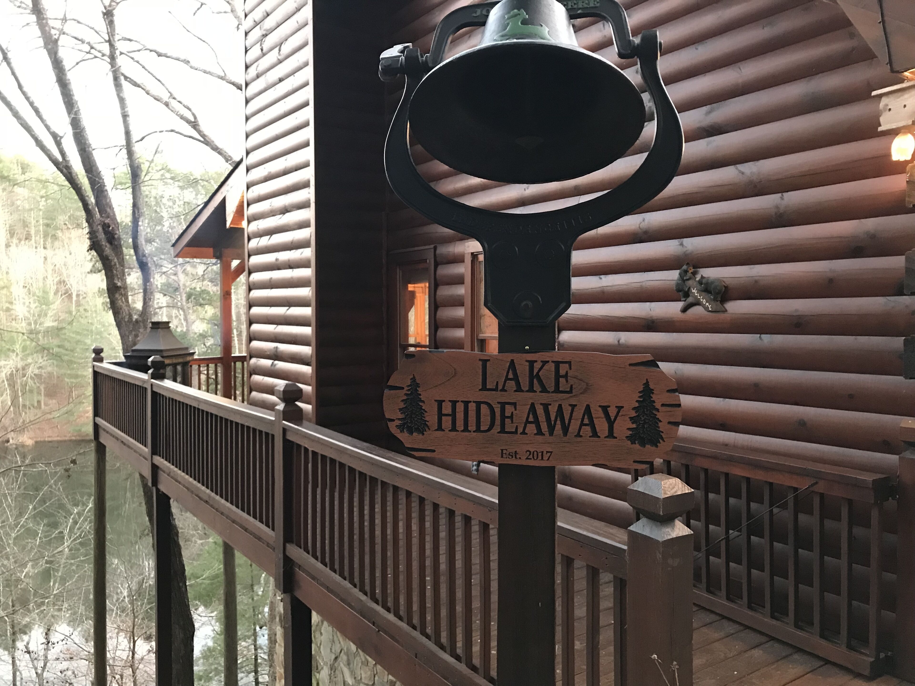 Un panneau en bois portant l’inscription « LAKE HIDEAWAY » et un symbole représentant un arbre, indiquant la présence d’un chalet ou d’une cabane.