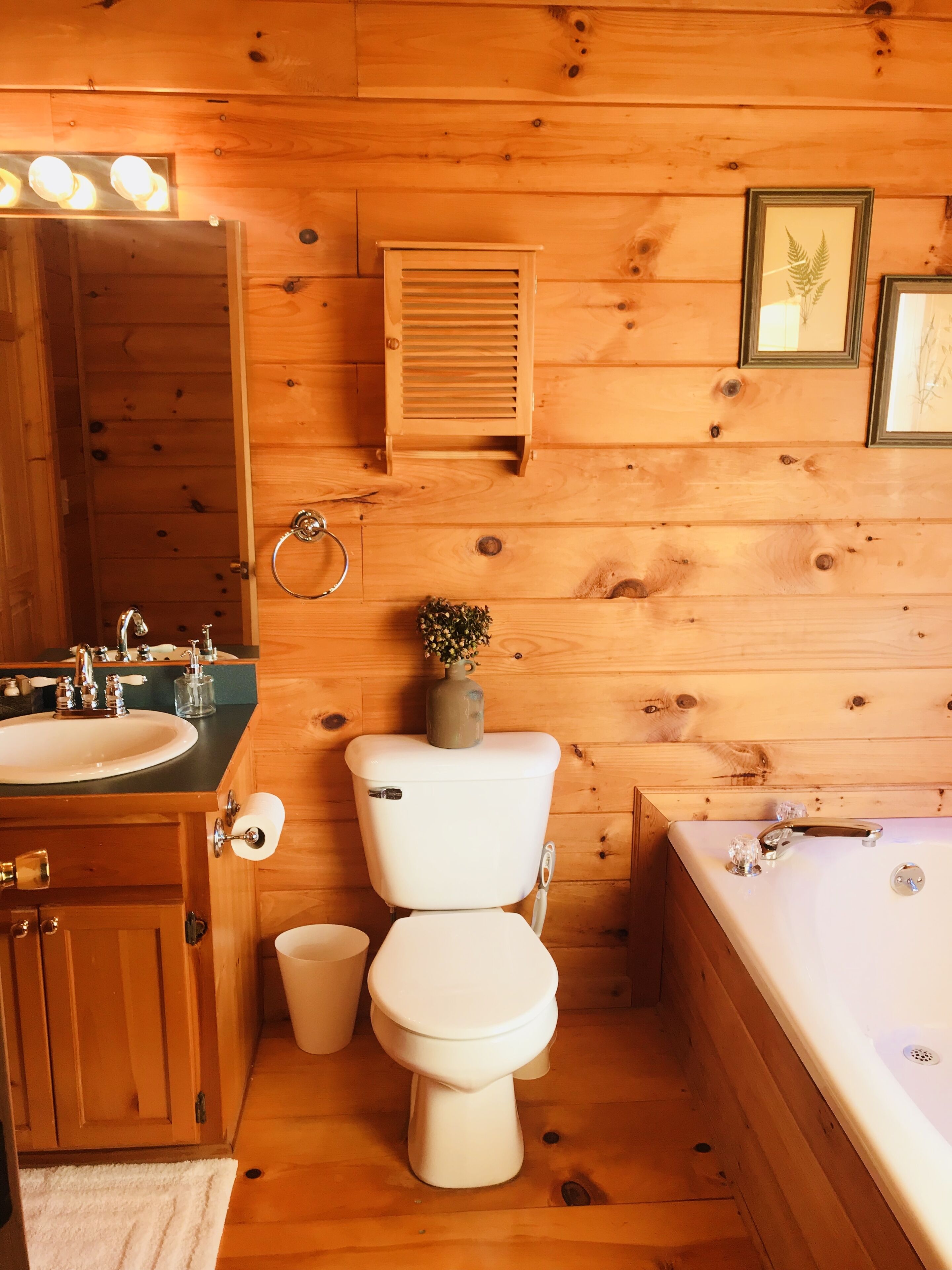A wooden cabin bathroom with a sink, toilet, and bathtub.