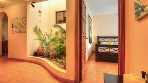 A hallway with a curved wall, a bed with a patterned headboard, and a small table with candles. - Heaven On Earth! Perfect Get-Away! Gorgeous Beach. Pool. Couples &/or Families. (Samara)