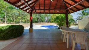 A covered outdoor area with a pool, patio furniture, and a view of the surrounding greenery. - Heaven On Earth! Perfect Get-Away! Gorgeous Beach. Pool. Couples &/or Families. (Samara)