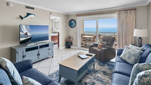 A living room with a television, sofa, coffee table, and a view of the ocean through a sliding door. - 🌴 Islander #507 – Fresh, Stylish & Ready for Beach Fun! 🌊✨ (Destin)