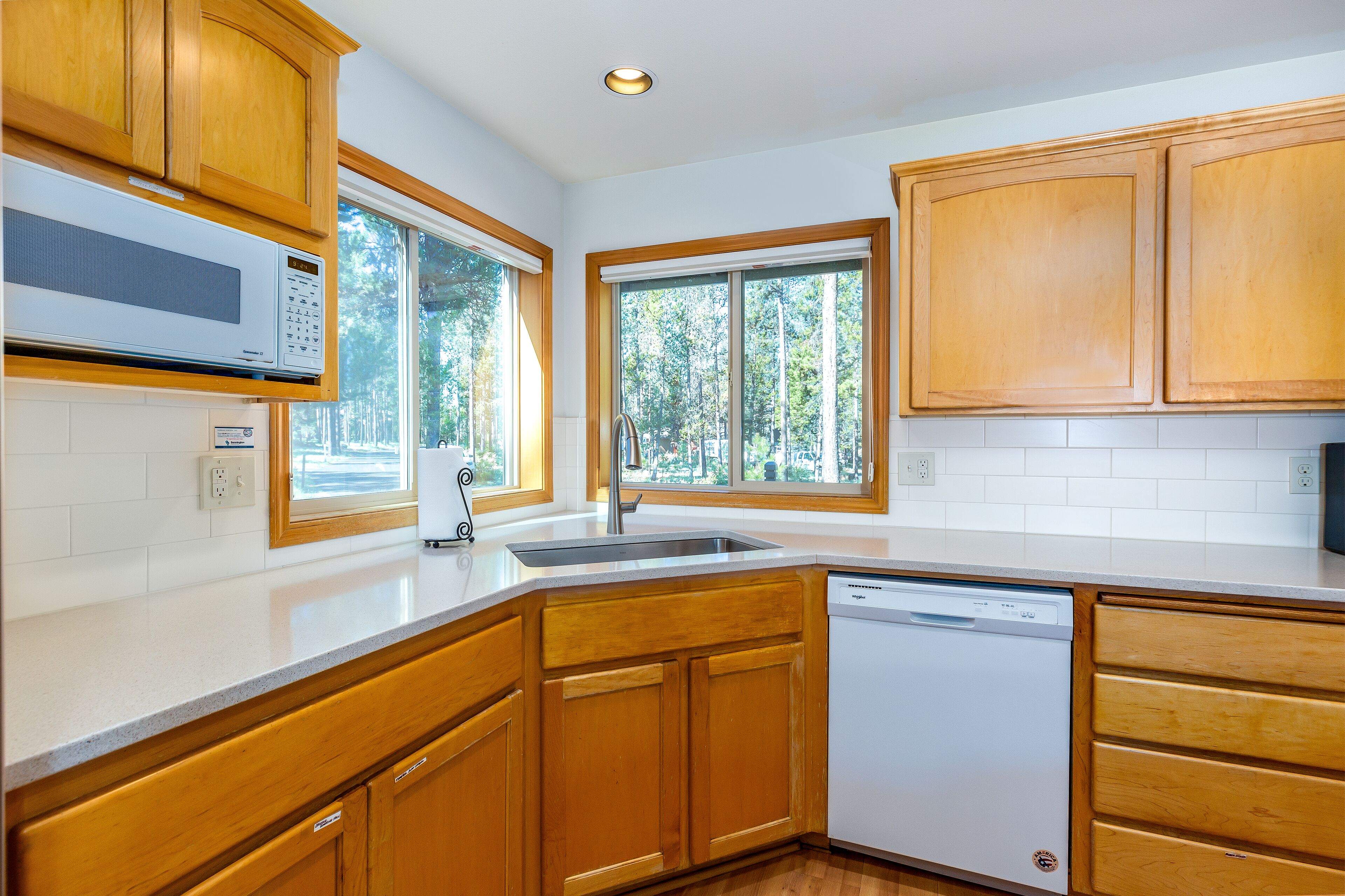 A kitchen with wooden cabinets, a built-in microwave, and a dishwasher.