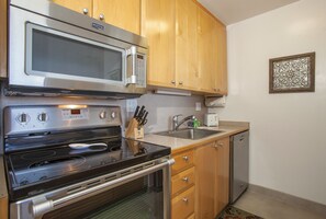 Kitchen features an oven, stainless steel sink, and a microwave above the stovetop.