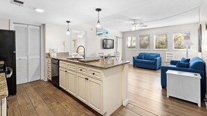 Un salón amplio con cocina, sofás azules y una isla blanca.
