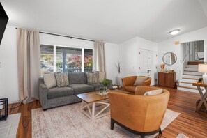 Uma sala de estar moderna com sofá, poltrona, mesa de centro e escada que dá acesso a outro andar.