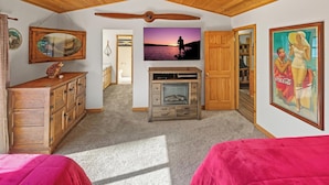 Una habitación con techo de madera, chimenea, televisor y puerta que da a otra habitación.