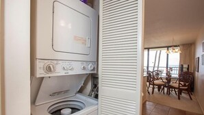 Un área de lavandería con lavadora y secadora, un comedor con sillas y una mesa, y vistas a través de una ventana.