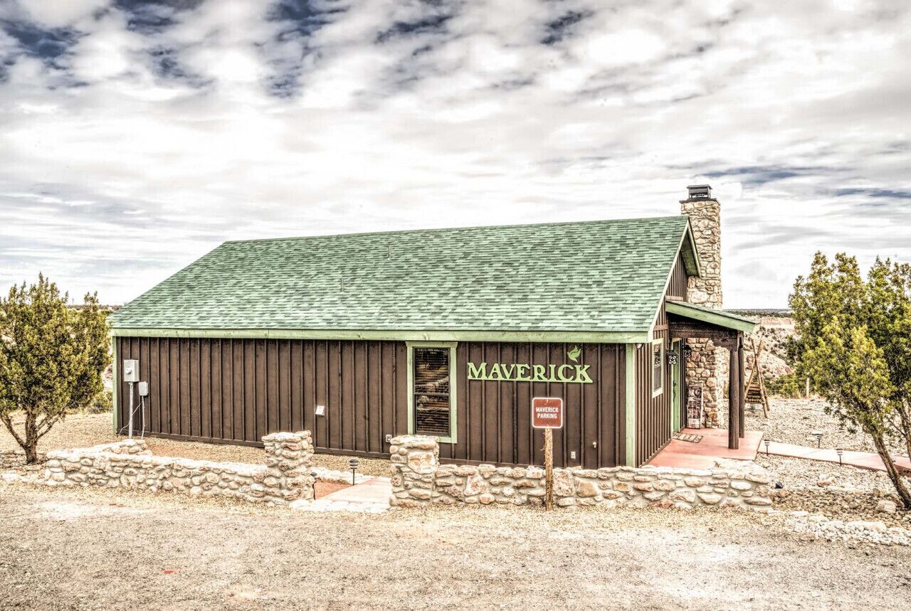 A building labeled "MAVERICK" with a stone chimney, a green roof, and a sign indicating "MAVERICK PARKING."