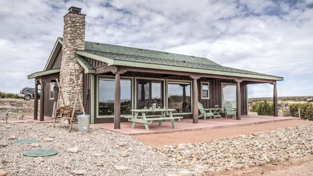A rustic cabin with a stone chimney, large windows, and a covered patio with picnic tables. - Maverick cabin North Rim (Canyon)