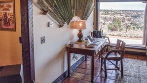 A room with a wooden table, a lamp, and a laptop. There is a window with a view of a rocky landscape. - Maverick cabin North Rim (Canyon)