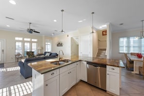A modern kitchen with a central island, white cabinetry, stainless steel appliances, and pendant lighting. - For Shore: Sleeps 10, steps to beach, heated pool! (Holmes Beach)