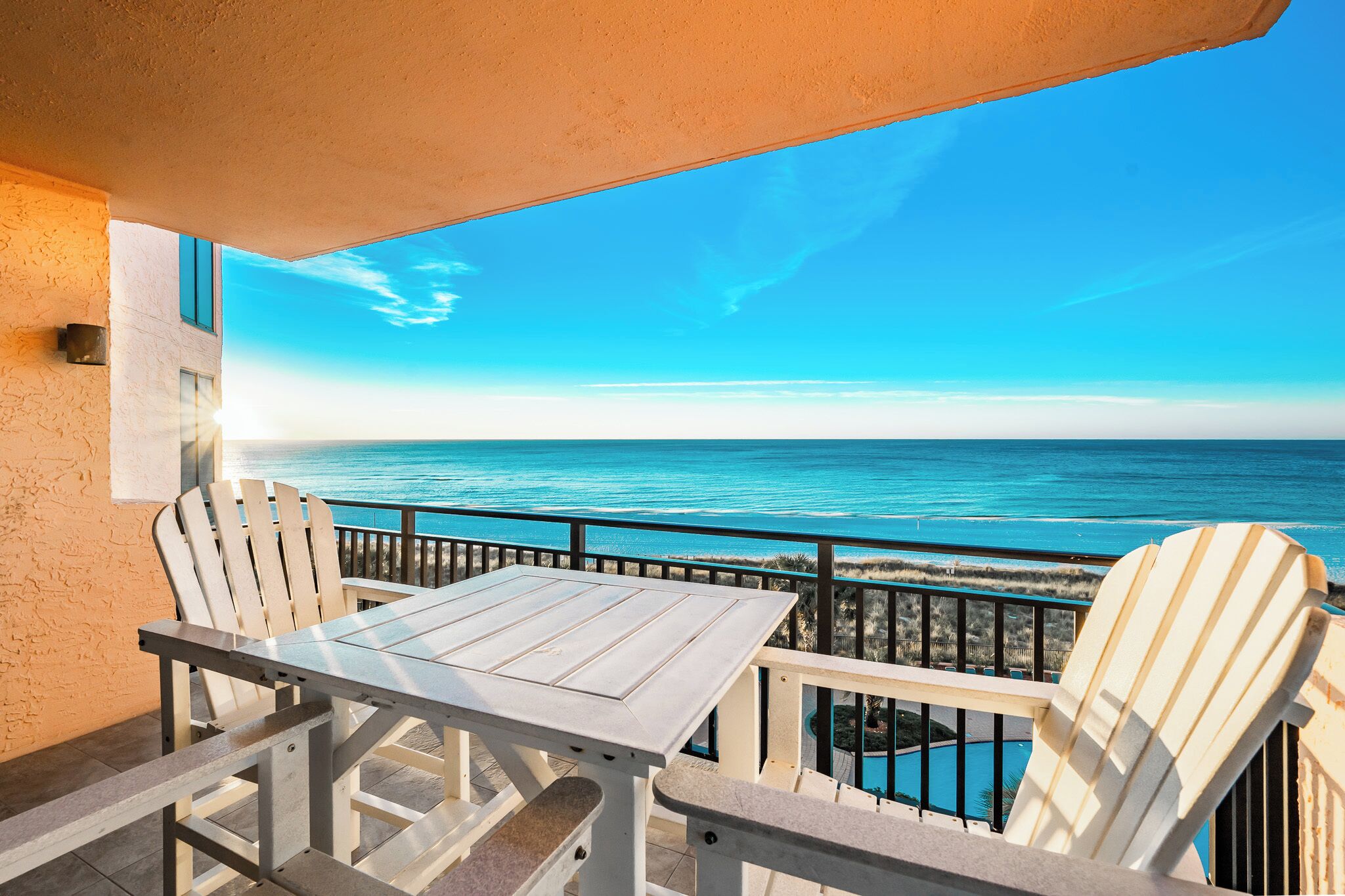Een balkon met uitzicht op de oceaan, een tafel en twee stoelen.