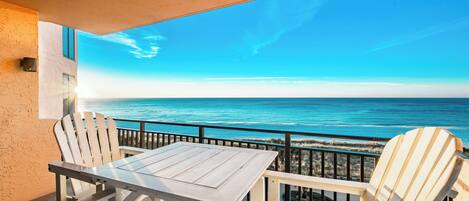 Een balkon met uitzicht op de oceaan, een tafel en twee stoelen.