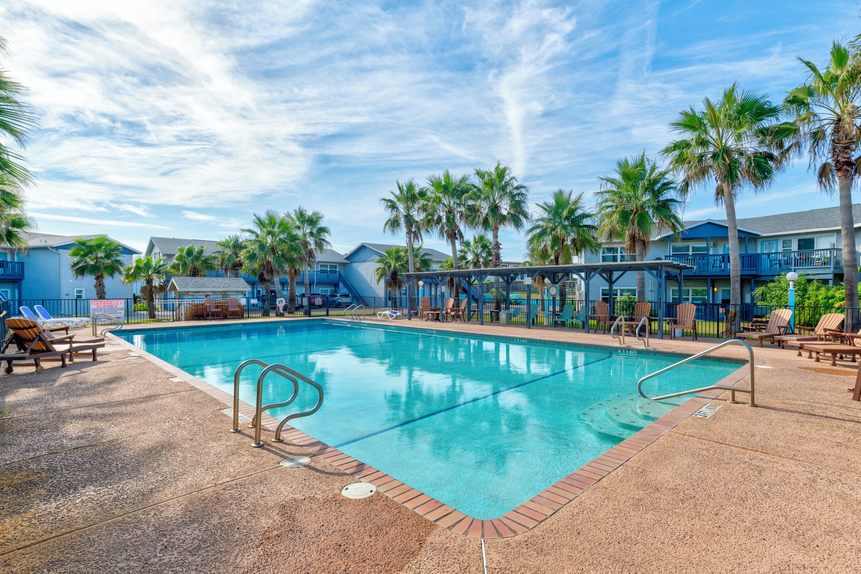 A swimming pool with lounge chairs and palm trees.