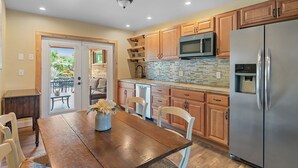 A kitchen with wooden cabinets, a stainless steel refrigerator, a microwave, and a brick backsplash.