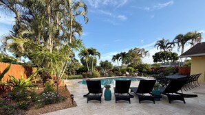 A poolside area with lounge chairs, a pool, and tropical plants.