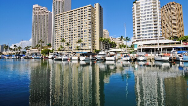 A marina with several boats docked, surrounded by high-rise buildings. - Experience the vibrant energy of Waikiki, featuring city views and close to beach! (Honolulu)