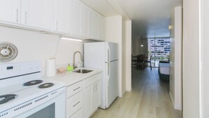 A modern kitchen with white cabinets, a stove, a refrigerator, and a sink. - Experience the vibrant energy of Waikiki, featuring city views and close to beach! (Honolulu)
