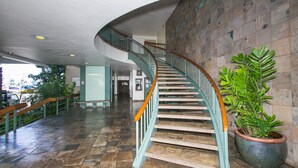 A curved staircase with wooden handrails and a potted plant beside it. - Experience the vibrant energy of Waikiki, featuring city views and close to beach! (Honolulu)