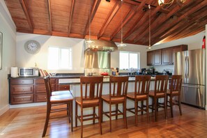 A spacious kitchen with wooden cabinets, a stainless steel range hood, and a large island with bar stools. - Racer Five ~ Fantastic Family Home Close to Town, River and Wineries (Guerneville)