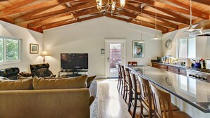 A spacious living area with a large sofa, a television, and a kitchen with a bar. - Racer Five ~ Fantastic Family Home Close to Town, River and Wineries (Guerneville)