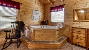 Un baño de cabaña de madera con una bañera de madera, una silla y un tocador con cajones.