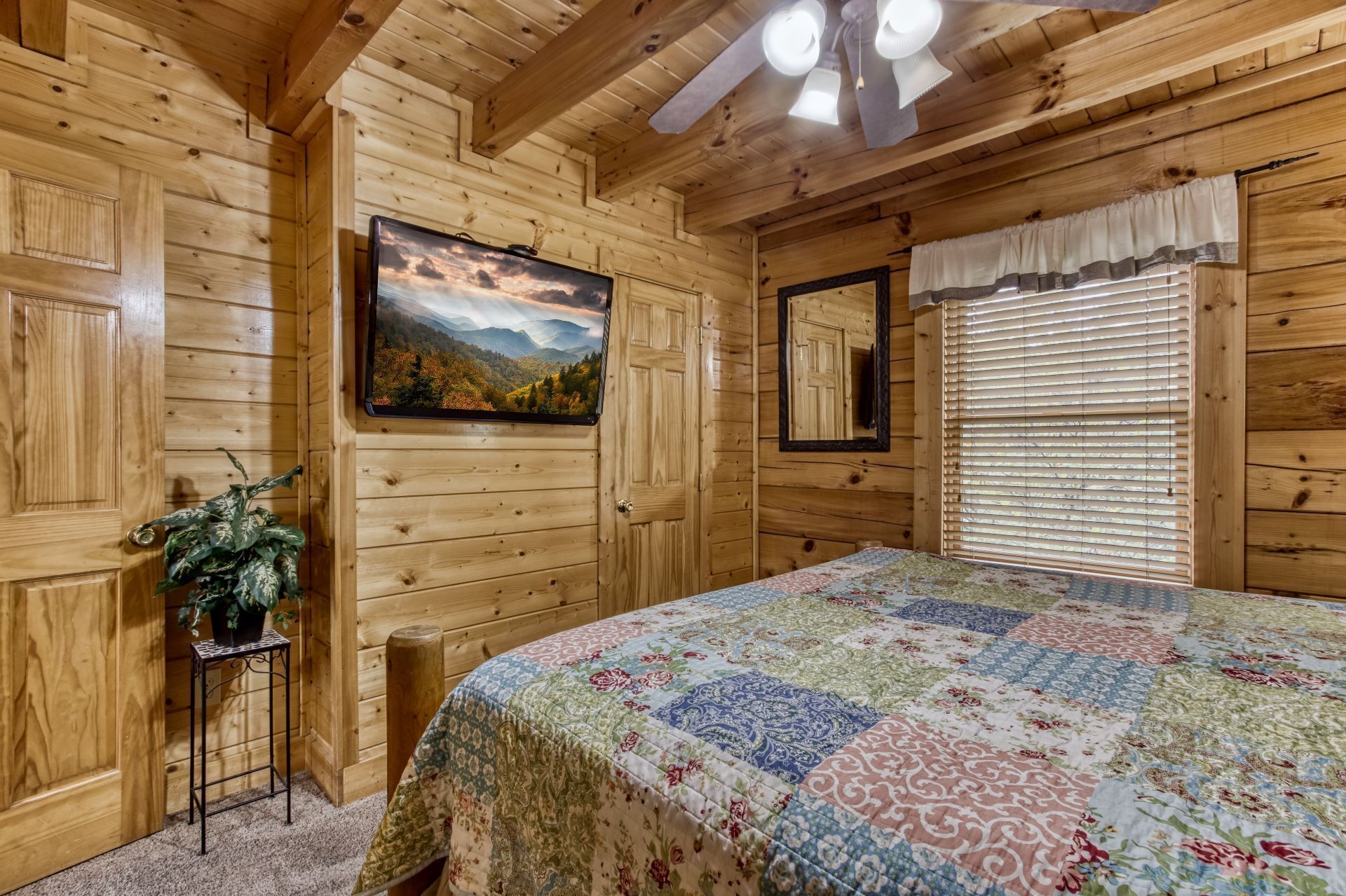 Un dormitorio de cabaña de madera con cama, un cuadro, un espejo y una ventana con persianas.