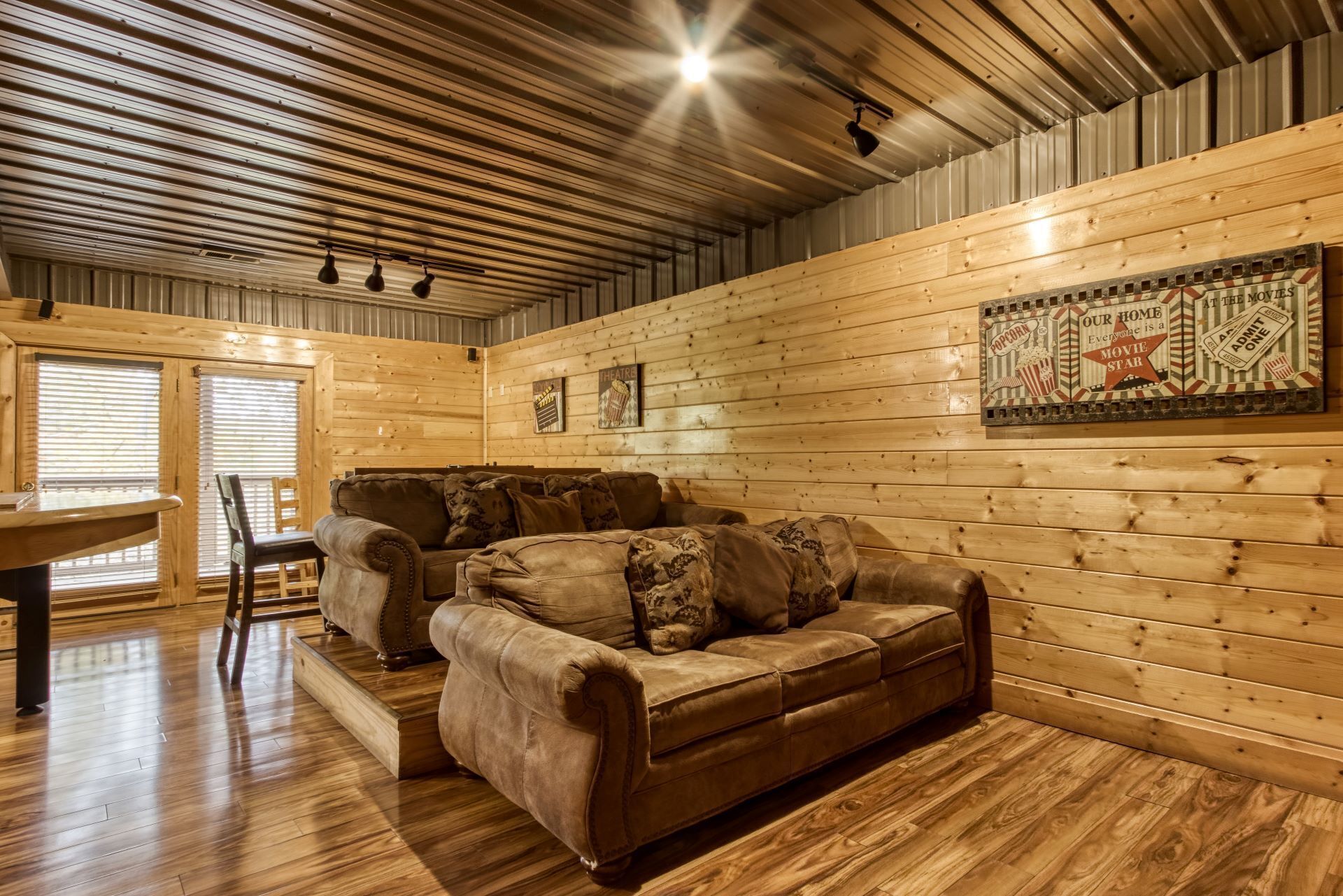 Interior acogedor de una cabaña de troncos, con un sofá, una mesa de comedor y un cartel que dice 'Palomitas'.