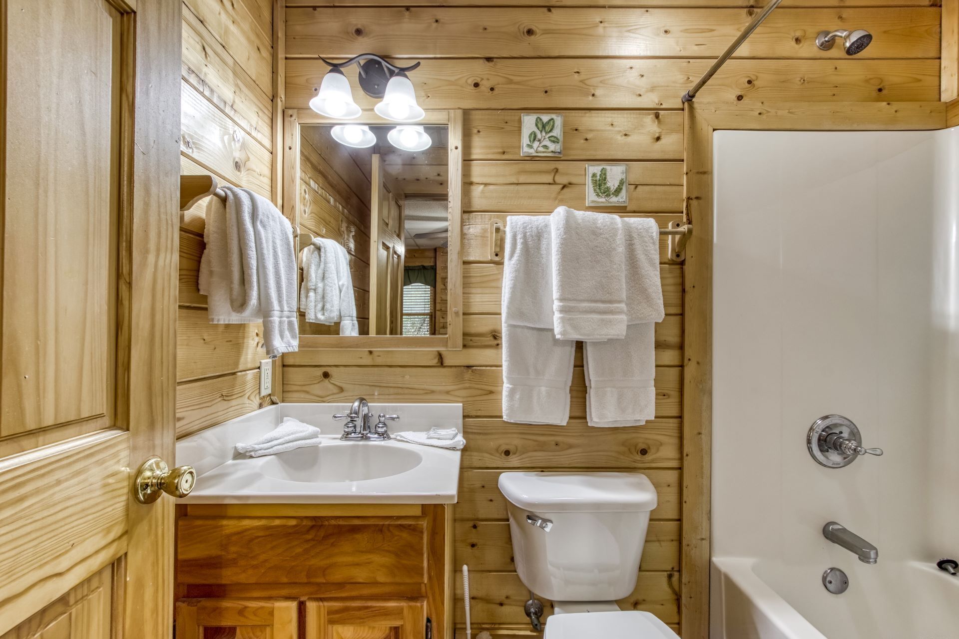 Un bagno in una baita di legno, con lavandino, WC e vasca da bagno.