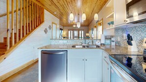 A modern kitchen with a wooden ceiling, built-in cabinets, a central island with a sink, and a dishwasher. - Townhome Located in Town, Close to beach, Shared Pool, Pet Friendly (Port Aransas)