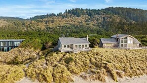 A coastal property with multiple houses, a sandy beach, and a forested hillside. - la Playa Luna-Family sized beachfront home (Cloverdale)