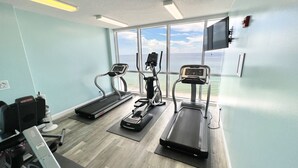 Une salle de remise en forme équipée de tapis de course, d’un vélo d’appartement et d’un rameur.