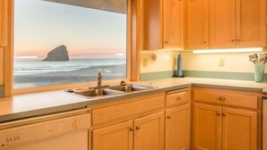 Una cucina con mobili in legno, un lavello doppio e una finestra vista oceano.