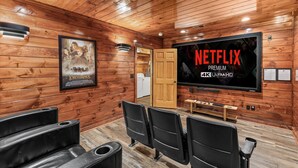 A wooden interior with a large flat-screen TV displaying "NETFLIX PREMIUM 4K ULTRAHD" and a poster of "The Lord of the Rings".