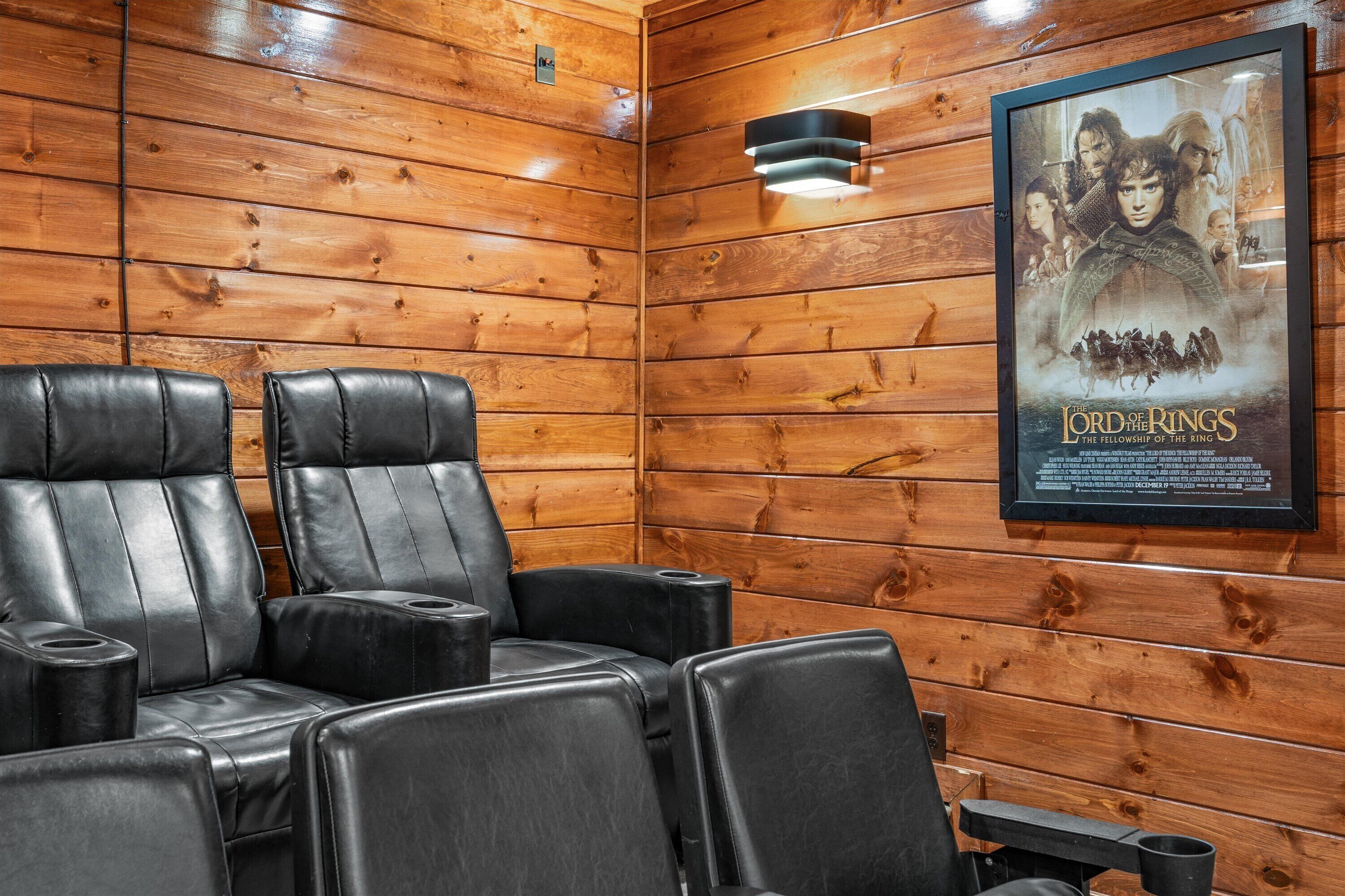 Ein Zimmer mit Holzwänden, schwarzen Ledersesseln und einem Poster von 'Der Herr der Ringe: Die Gefährten'.