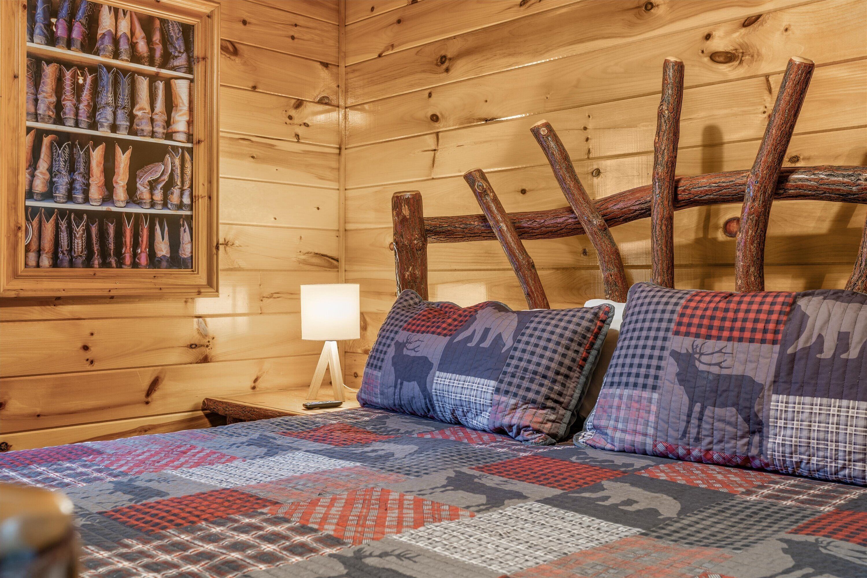 L'intérieur d'un chalet en bois, avec un lit, un porte-chaussures fixé au mur et une table de chevet avec une lampe.