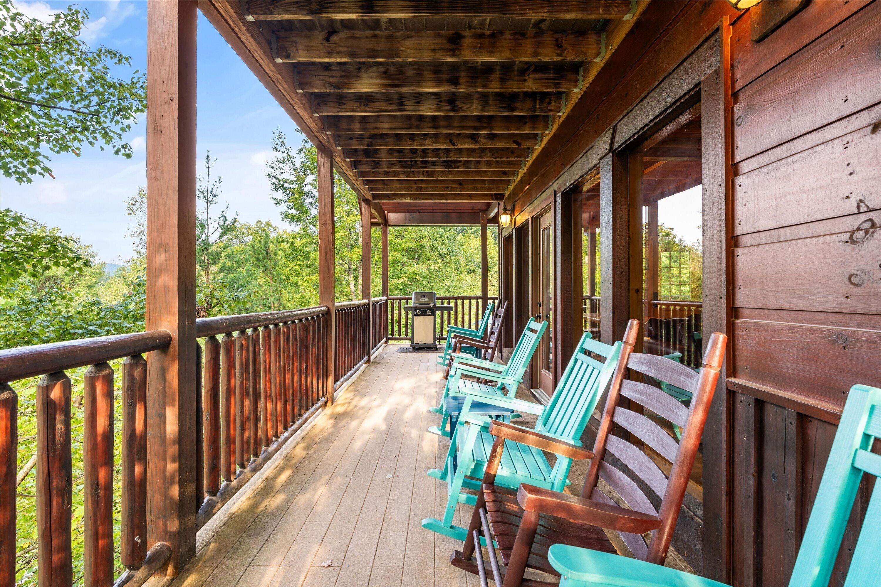 A wooden deck with chairs and a grill.