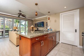 A kitchen with a granite countertop, wooden cabinets, a ceiling fan, and a large sliding door.