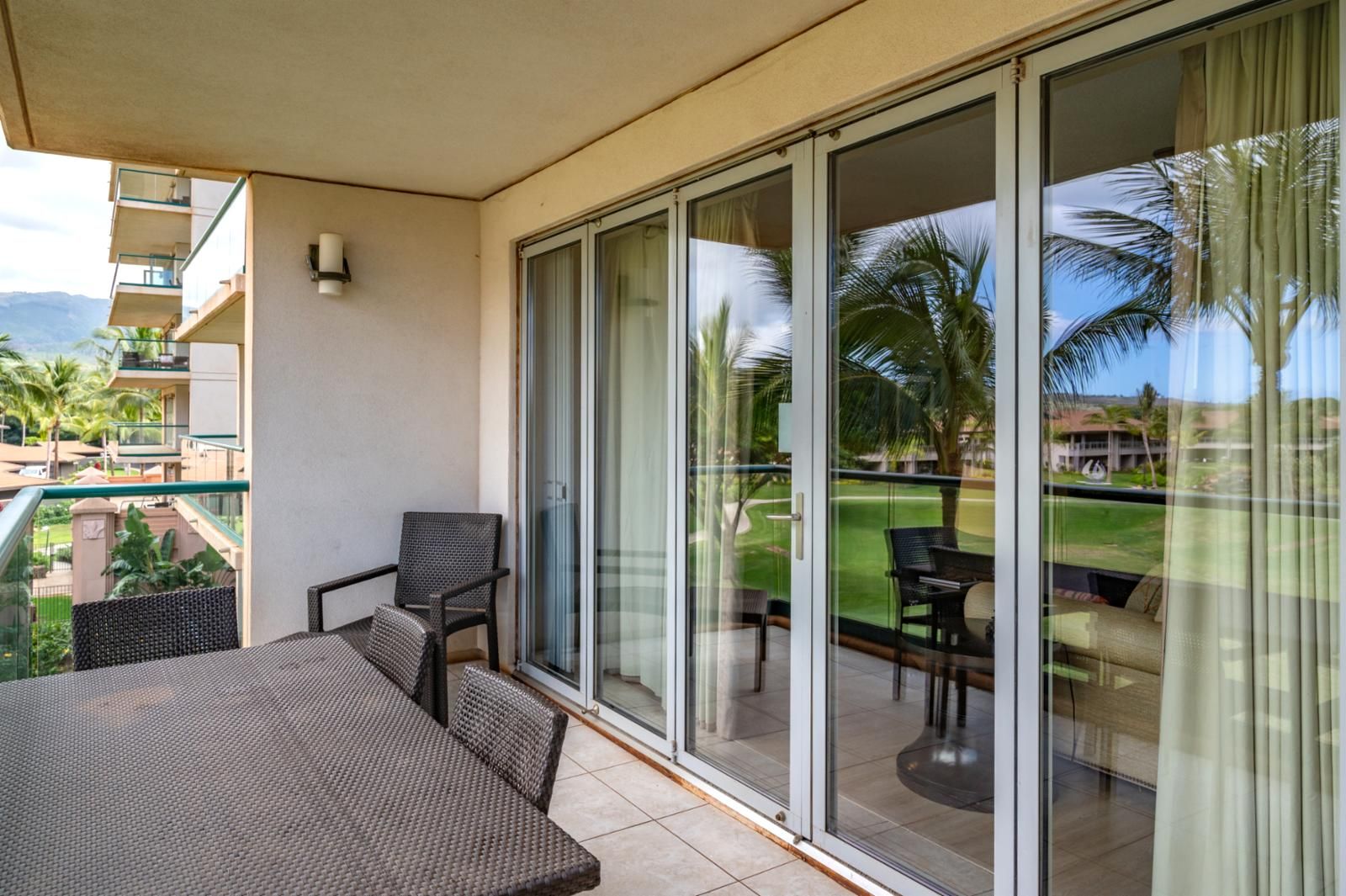 A balcony with a table and chairs, a sliding glass door, and a view of a golf course.