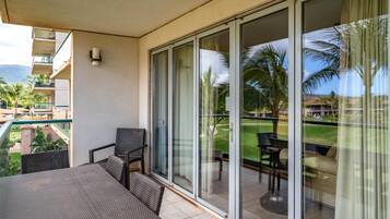 A balcony with a table and chairs, a sliding glass door, and a view of a golf course.