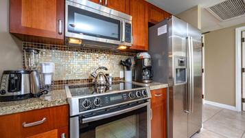A modern kitchen with stainless steel appliances, wooden cabinets, and a tiled backsplash.