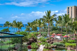 A resort with a view of the ocean, palm trees, and a building with a red roof.