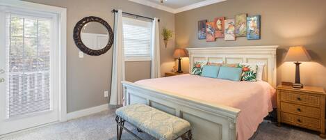 A bedroom with a bed, bench, bedside tables, a ceiling fan, and artwork on the wall.