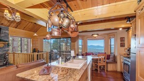 A spacious kitchen with granite countertops, wooden cabinets, and copper cookware hanging from the ceiling.