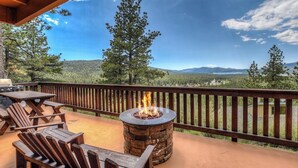 A wooden deck with a stone fire pit and outdoor seating.