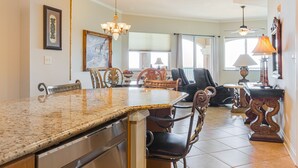 Une cuisine spacieuse dotée de plans de travail en granit, un coin repas avec des chaises décoratives et un lustre.