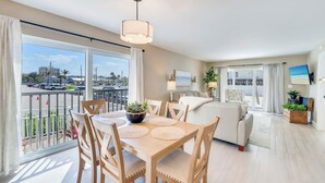 Een moderne woonkamer met een eethoek, grote ramen en een balkon met uitzicht op de stad.