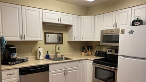 A kitchen with white cabinets, stainless steel appliances, a dishwasher, a microwave, and a refrigerator.